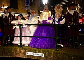 Mensen verkleed als winterkoningin en koning staan op een brug